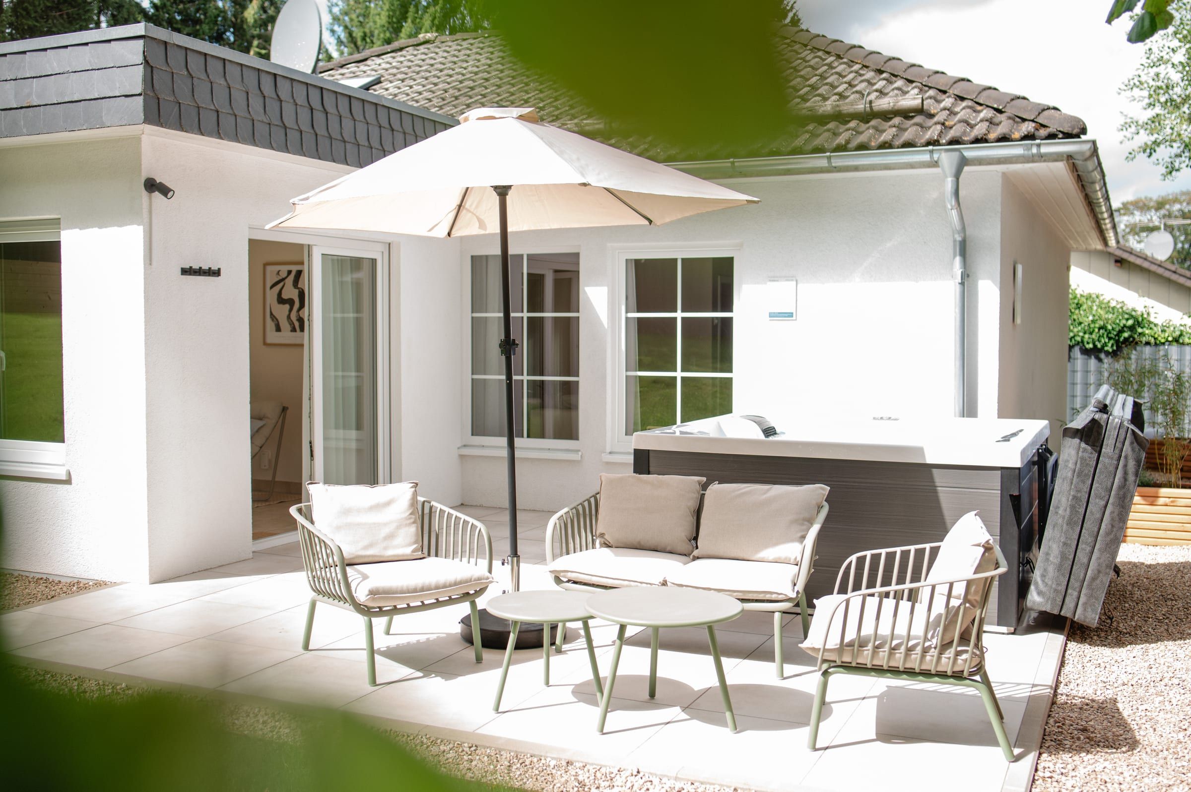 Gepflasterte Terrasse mit Lounge, Sonnenschirm und Whirlpool, Garten ringsum