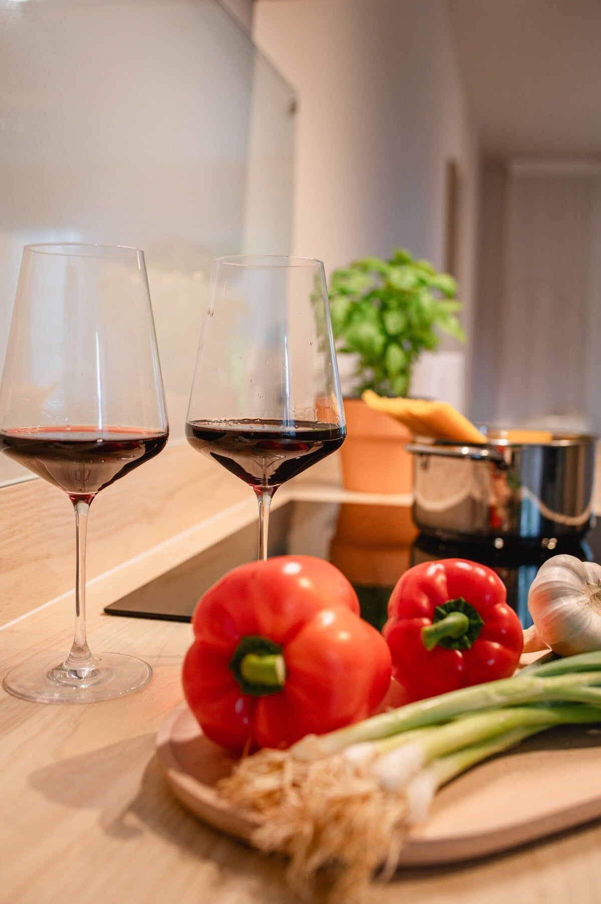 Weingläser, Paprika und Zwiebeln beim Kochen