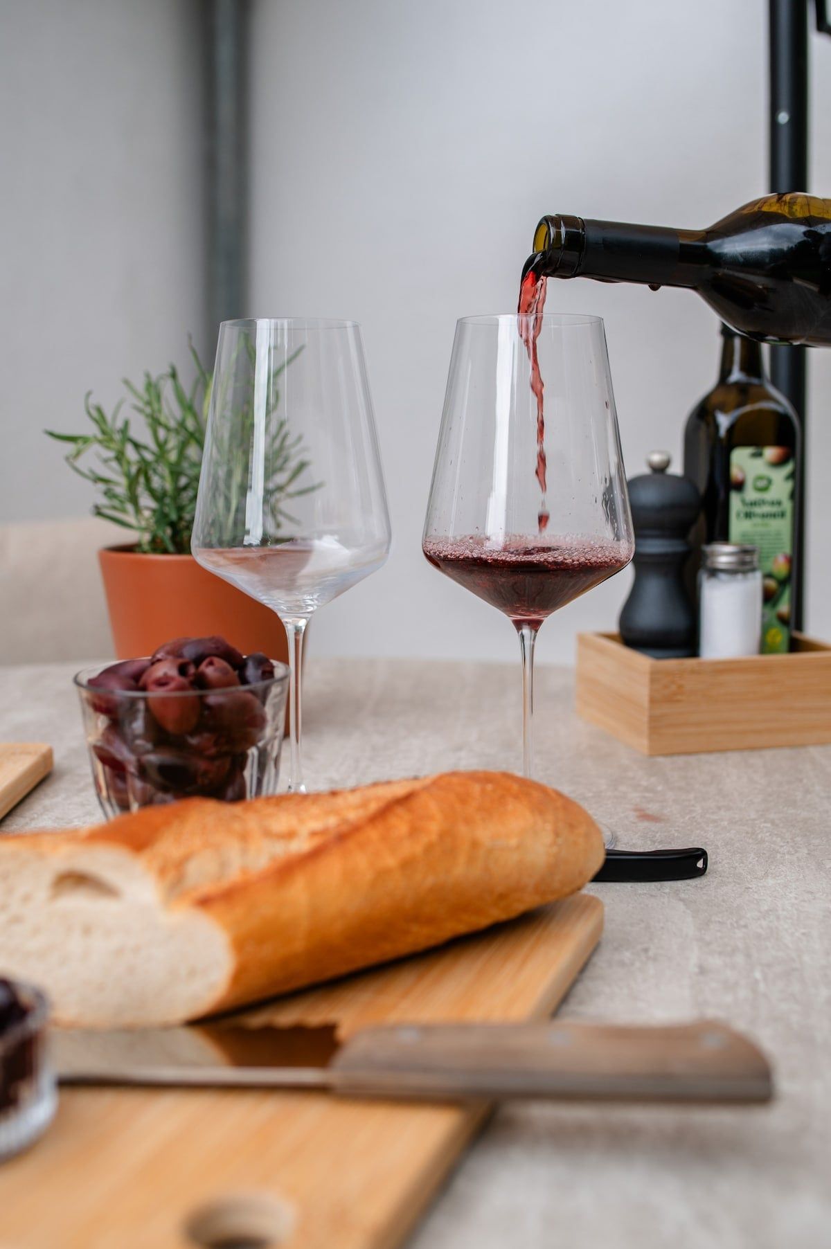 Rotwein wird auf der Terrasse eingeschenkt, dazu frisches Brot und Kräuter